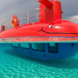 The semi-submarine, red hull at the surface and glazed cabin below the turquoise water