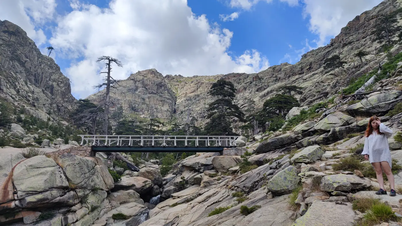 The footbridge on the Radule path, a railed bridge over the stream in a granite cirque, with a walker for scale
