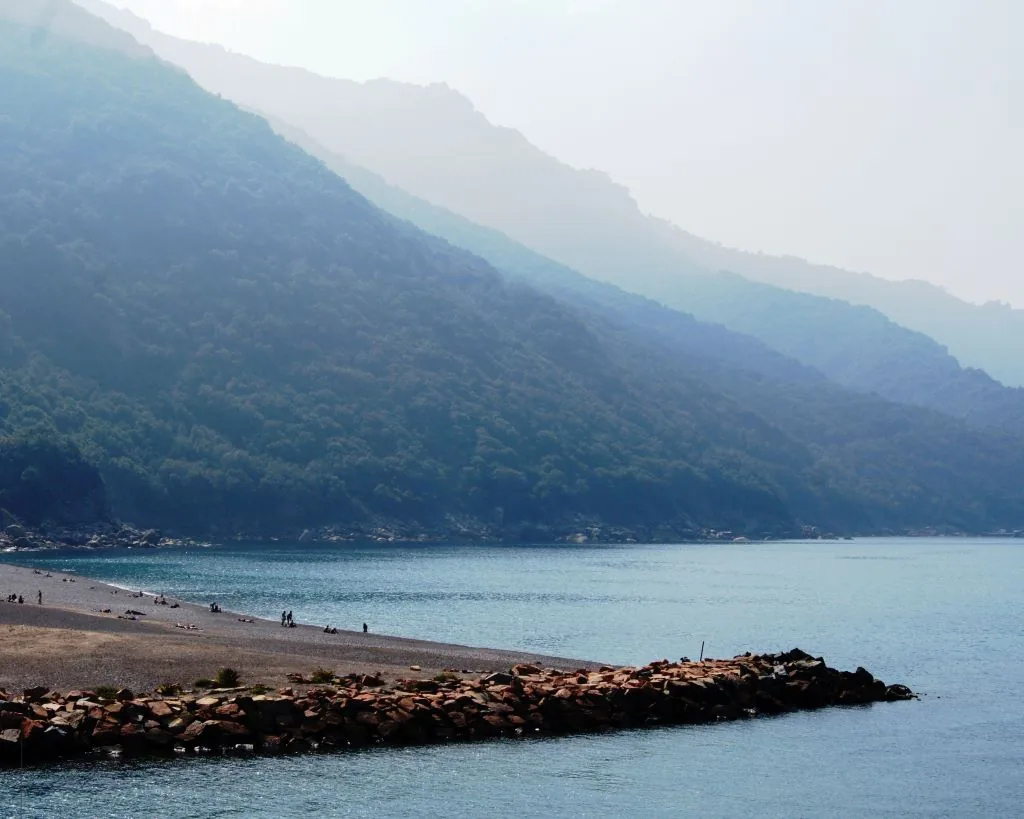 Spiaggia di ciottoli di Porto con il suo molo e le montagne del golfo, Corsica