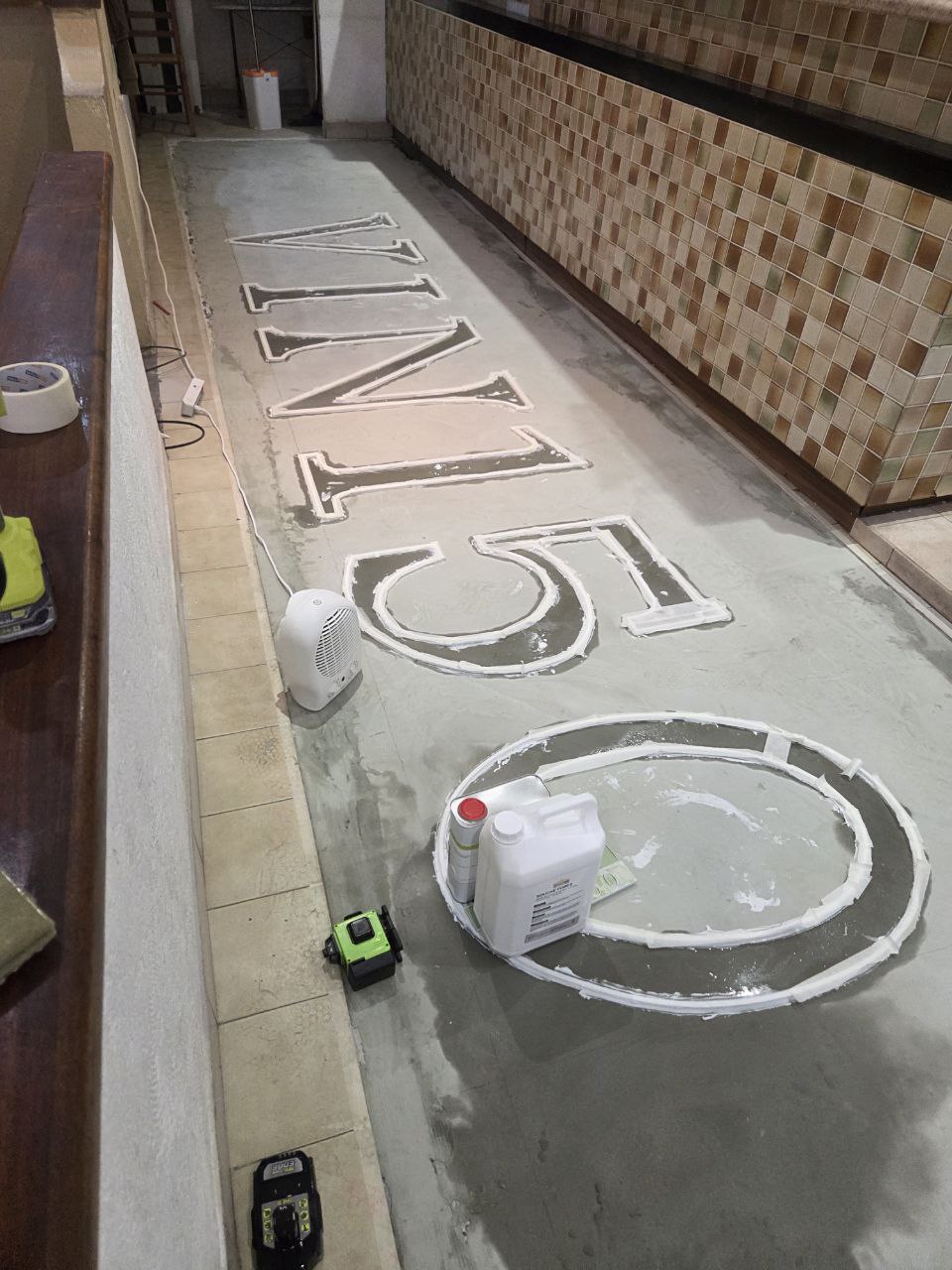 Sol en ragréage coloré en cours de séchage avec les lettres VIN 150 visibles